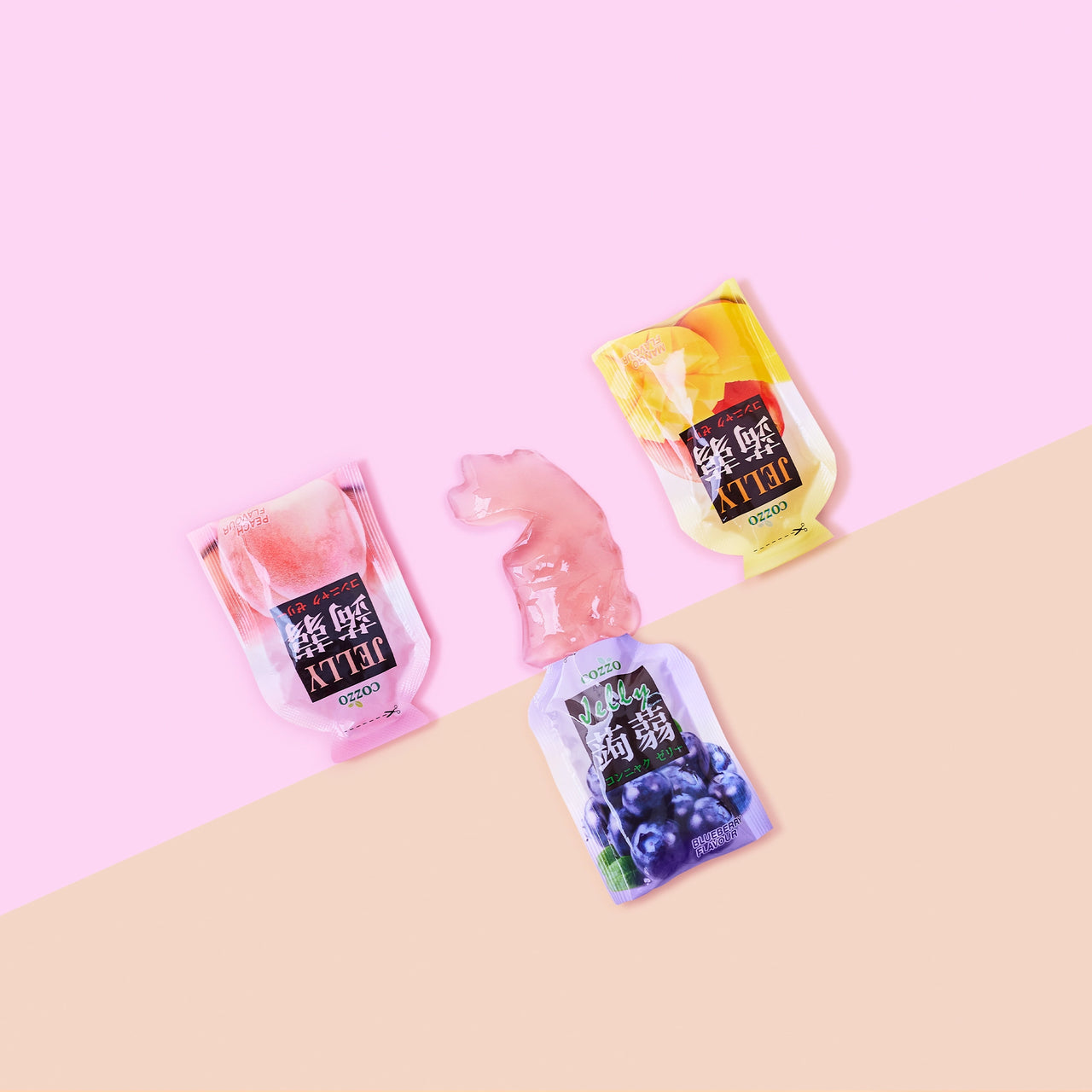 Konjac jelly / Konnyaku jelly flat lay on a two-tone pink and beige background, with three Cozzo jelly pouches (peach, mango, and blueberry) and a glossy jelly piece placed in the center.

جيلي كونجاك / جيلي كوننياكو — صورة علوية على خلفية وردية وبيج، تظهر ثلاث أكياس جيلي Cozzo (خوخ ومانجو وتوت أزرق) مع قطعة جيلي لامعة في الوسط.