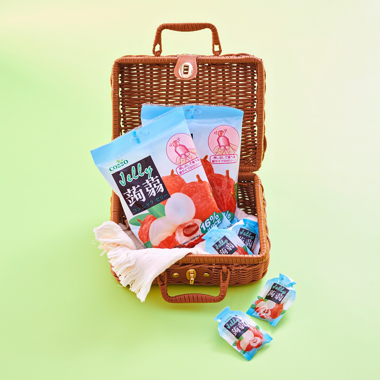 Keto friendly snacks styled photo of Cozzo konnyaku jelly lychee flavour pouches in an open wicker picnic case on a soft green background, with extra mini pouches and a folded cloth inside, showing lychee fruit artwork and “16% juice” on the packs.

سناكات كيتو — صورة بطابع بيكنك لجيلي كوننياكو Cozzo بنكهة الليتشي داخل حقيبة خوص مفتوحة على خلفية خضراء فاتحة، مع عبوات صغيرة إضافية وقطعة قماش، وتظهر رسمة الليتشي وعبارة “16% عصير” على التغليف.